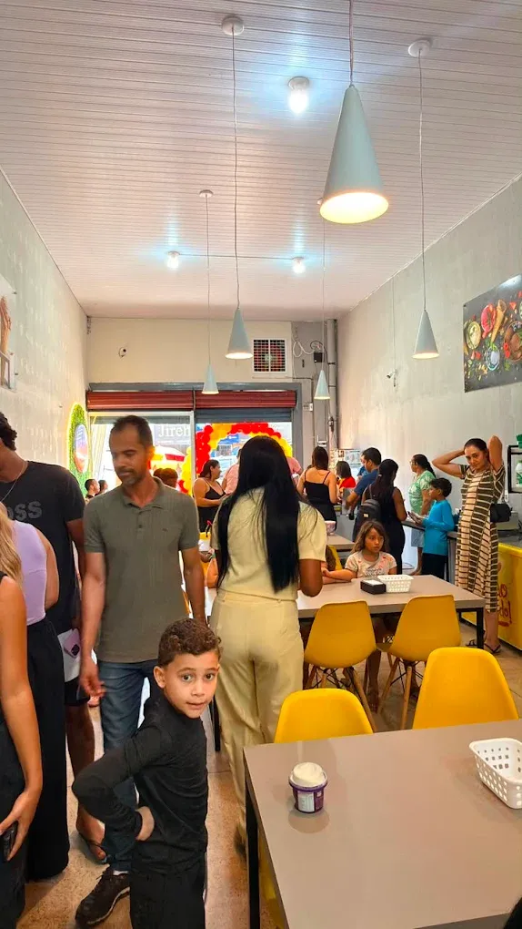 Clientes no salão da loja, com mesas e cadeiras amarelas